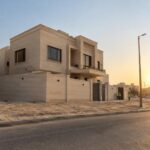 فيلا جديدة مكتملة الواجهة في الكويت قبيل العصر مع عمال بخوذ أمان من بعيد وعمود خدمات في الشارع